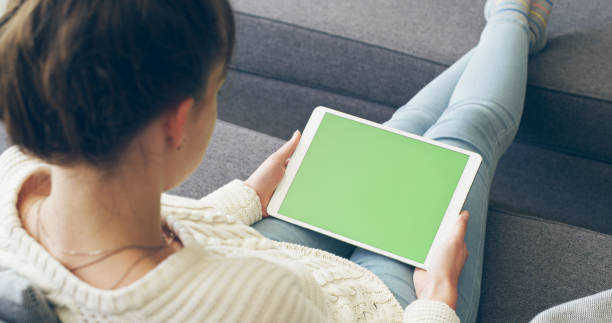High angle shot of an attractive young woman using a digital tablet while relaxing in her living room at home