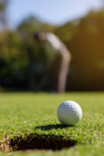 istock Golfer putting golf ball into hole 1193070999