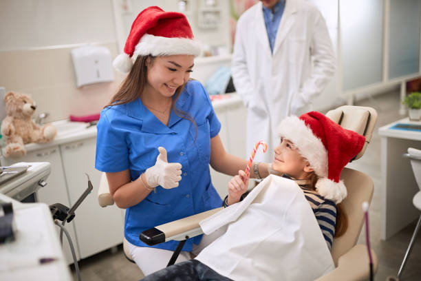 Dentist woman in Santa hat examining tooth patient in ambulant. Dentist woman in Santa hat examining tooth young patient in ambulant. ambulant patient stock pictures, royalty-free photos & images