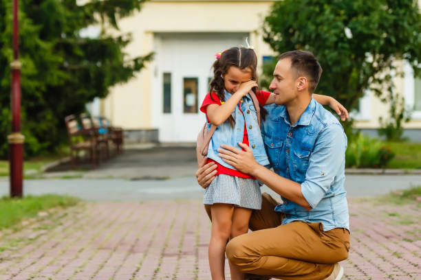 Pretty little girl crying because of bad mark while professional male teacher comforting her Pretty little girl crying because of bad mark while professional male teacher comforting her teacher classroom child education stock pictures, royalty-free photos & images