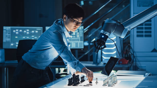 ingeniero profesional de desarrollo japonés está probando una interfaz de inteligencia artificial jugando ajedrez con un brazo robótico futurista. están en un laboratorio de investigación moderna de alta tecnología. - chess pawn red blue leisure games fotografías e imágenes de stock