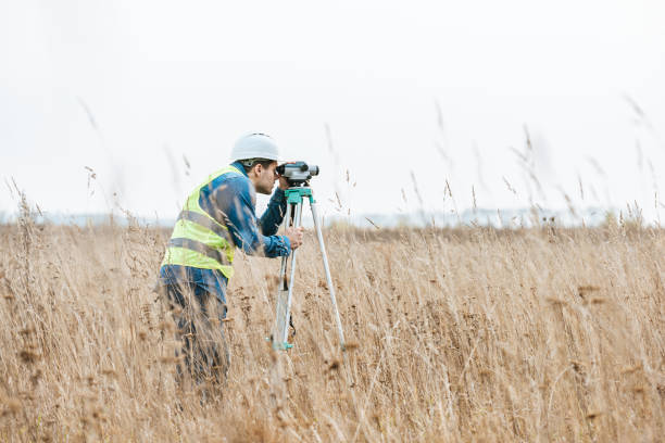 istock Side view of surveyor with digital level measuring field 1193074255