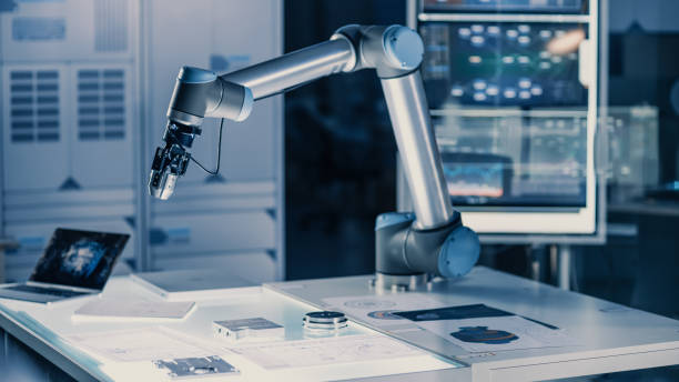 istock Futuristic Artificial Intelligence Robotic Arm Operates and Moves a Metal Object, Picks It Up and Puts it Down. Scene is Taken in a High Tech Research Laboratory with Modern Equipment. 1193074311