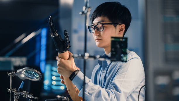 istock Futuristic Prosthetic Robot Arm Being Tested by a Professional Japanese Development Engineer in a High Tech Research Laboratory with Modern Computer Equipment. He is Satidfied with the Result. 1193074327