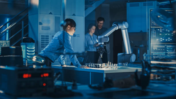 ingeniero profesional de desarrollo japonés está probando una interfaz de inteligencia artificial jugando ajedrez con un brazo robótico futurista. están en un laboratorio de investigación moderna de alta tecnología. - chess pawn red blue leisure games fotografías e imágenes de stock