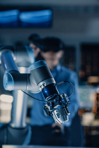 istock Vertical Close-up Shot of a Futuristic Robotic Arm Controlled by Professional Development Engineer with Virtual Reality Headset and Joysticks in a High Tech Research Laboratory with Modern Equipment 1193074376