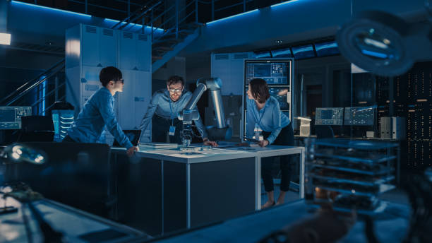 istock Futuristic Robotic Arm is Moving and Placing a Metal Object. Senior Engineer Talks Through This Advanced Process with His Diverse Team. They are in High Tech Research Laboratory with Modern Equipment 1193075031