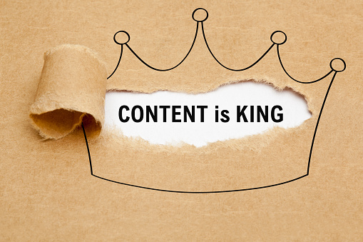 Text Content is King appearing behind torn brown paper in crown drawing. Concept about the importance of Content in internet marketing.