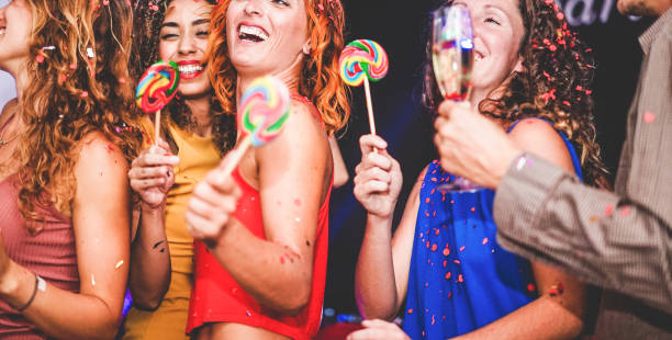istock Young friends drinking champagne while dancing inside disco club - Happy people having fun eating candy lollipops at night party - Holidays and nightlife concept - Focus on red hair woman face 1193079515