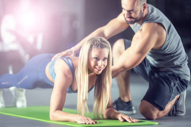 istock Coach trainer and sportswoman doing plank in gym. 1193088058