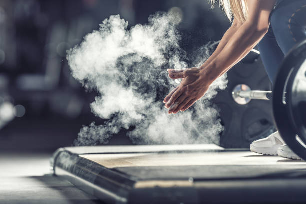 mujer levantadora de pesas muscular aplaudiendo antes del entrenamiento de barbell en el gimnasio con mancuernas. - levantamiento de potencia fotografías e imágenes de stock