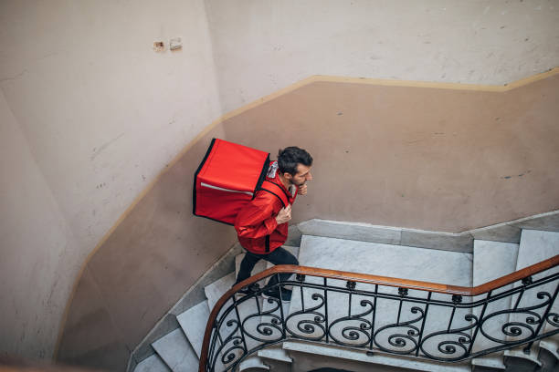 istock Pizza delivery guy climbing up the stairs in building 1193089712