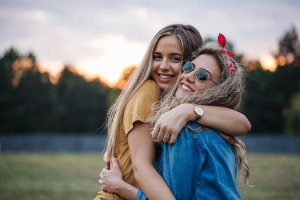 Beautiful young females embracing each other outdoors in nature.