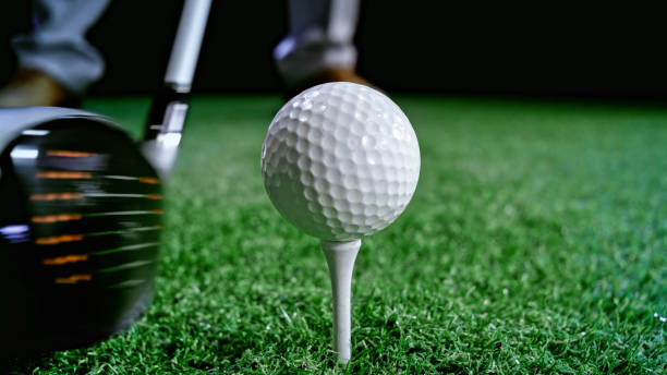 Golf ball on tee Close-up of golf ball on tee at night. night golf stock pictures, royalty-free photos & images