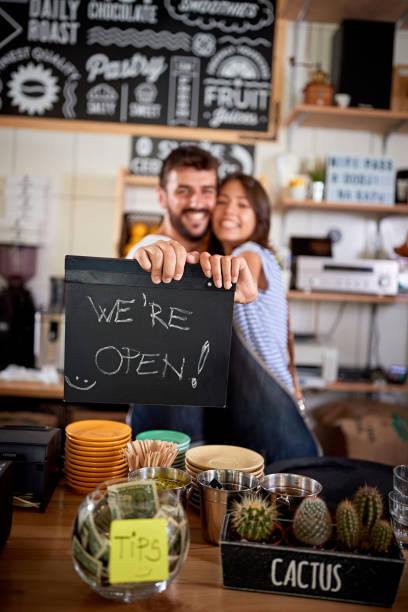 paar hält ein zeichen, wir sind offen - cafe laptop espresso business stock-fotos und bilder