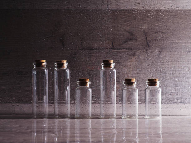 istock Small glass bottles with cork lid. empty bubbles in contoured light on wooden background, great banner, space for design 1193094193