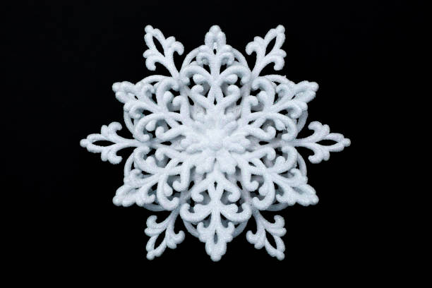 istock White decorative snowflake in sparkles isolated on black background 1193095391