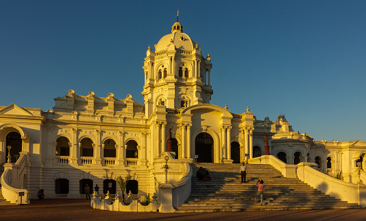 Agartala, Tripura/India - December 5 2017: The setting sun paints the Ujjayanta Palace yellow in the city of Agartala as visitors take pictures of themselves on its stairs.