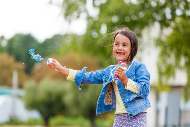 istock Little girl blowing soap bubbles 1193097230