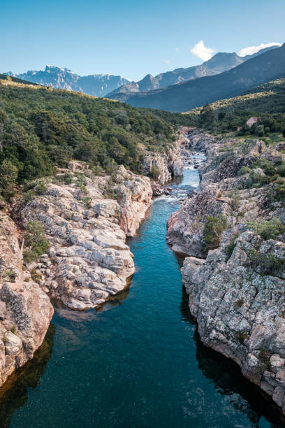 The crystal clear Fango river near Galeria in Corsica with the snow capped mountain of Paglia Orba in the distance