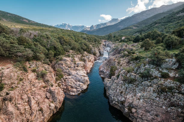 The crystal clear Fango river near Galeria in Corsica with the snow capped mountain of Paglia Orba in the distance