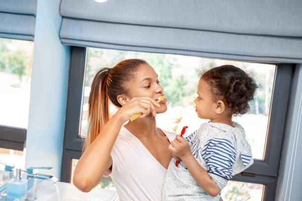 mother and little girl brushing teeth in bathroom - hairstyle crest imagens e fotografias de stock