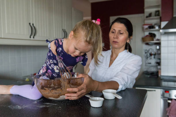 istock Girl with limited hand use mixes cake batter 1193114050