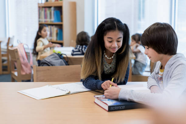 istock Girl smiles as she points out information to boy 1193114190