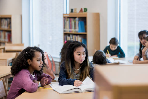 istock Two elementary age female friends work together in library 1193114191