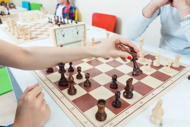 Photo of Woman making a chess move playing against a man