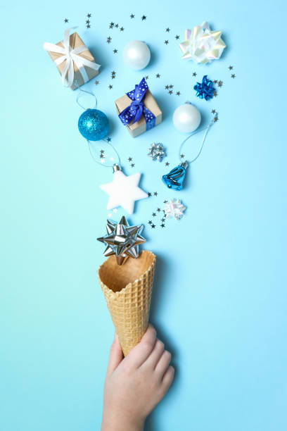 istock Hand holds a waffle cone with christmas elements on blue background. Holiday concept. 1193121653