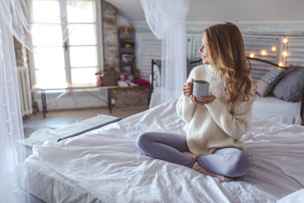 istock Beautiful young woman drinking coffee at home 1193123334