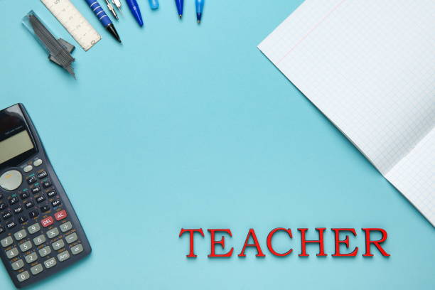 istock school background: calculator, notebook, writing supplies and word teacher on blue surface 1193125555