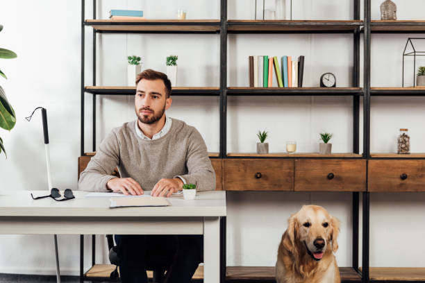 istock Blind man reading at table and golden retriever sitting beside 1193127178