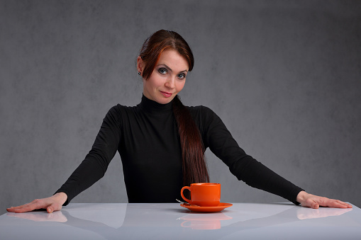 A lonely woman at a white glossy table with a Cup of coffee