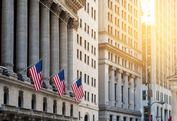 american flags flying in front of the historic buildings of wall street in the financial district of new york city - lower manhattan imagens e fotografias de stock