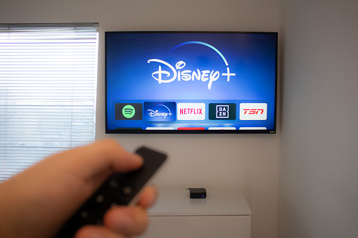Calgary, Alberta. Canada Dec 5 2019: Person holds an Apple TV remote using the new Disney+ app on a Vizio TV. Disney+ video streaming service will exclusively show Star Wars: Jedi Template Challenge.