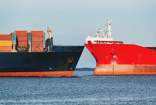 The bow of a container ship which is anchored in Vancouver Harbour with the Vancouver, British Columbia skyline in the background.