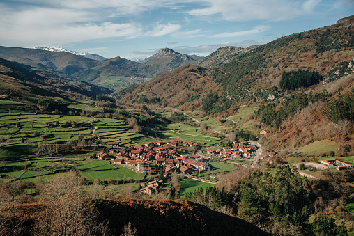 A typical landscape from the northern Spanish region of Cantabria, Spain: green fields, mountains and a typical village in a valley. The village in the picture is Carmona, which is known for its houses with typical architecture.