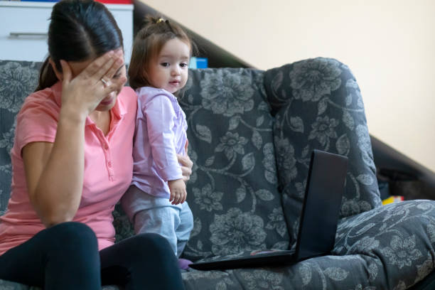 istock Mother  with her baby sitting on a sofa and working on a laptop 1193134797