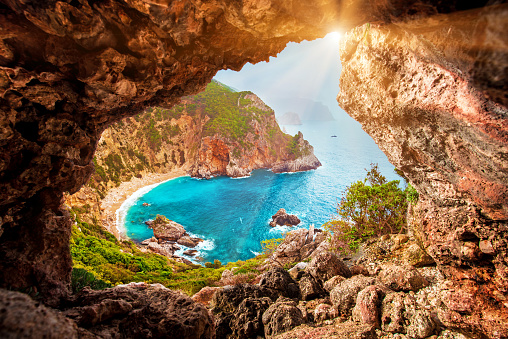 Beautiful magical view of the Gyali beach in Corfu, Greece through a hole in the rock at sunny day. amazing places. popular tourist atraction.