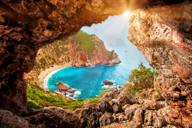 Beautiful magical view of the Gyali beach in Corfu, Greece through a hole in the rock at sunny day. amazing places. popular tourist atraction. Beautiful magical view of the Gyali beach in Corfu, Greece through a hole in the rock at sunny day. amazing places. popular tourist atraction. corfu stock pictures, royalty-free photos & images