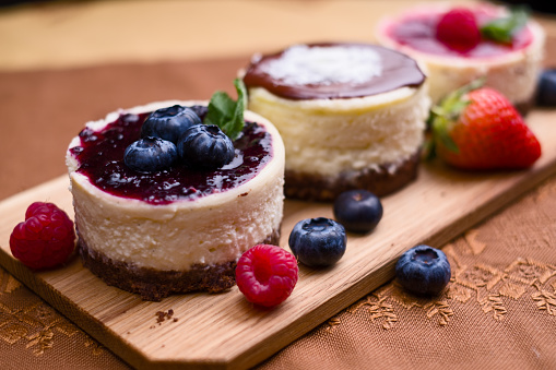 Small blueberry oval cheesecake with blueberry filling and berries decoration on wooden plate