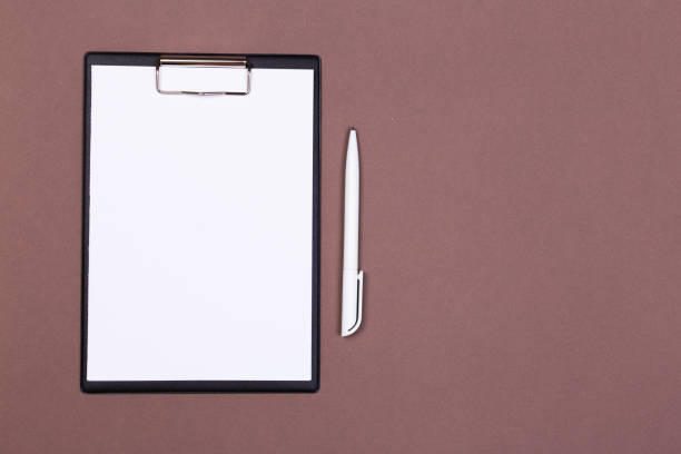 istock Clipboard with white sheet and pen on a colored background. View from above. space for text 1193138786