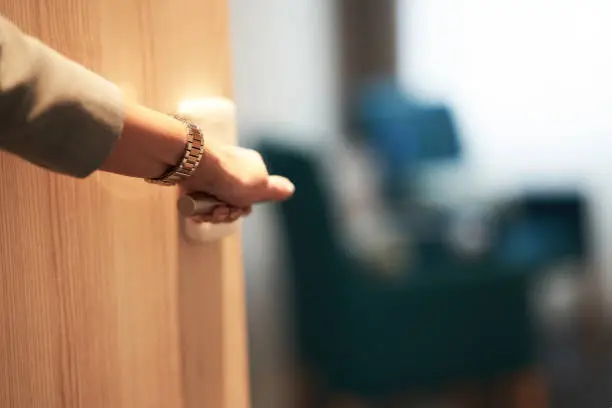 Photo of Half-open door of a hotel bedroom with hand