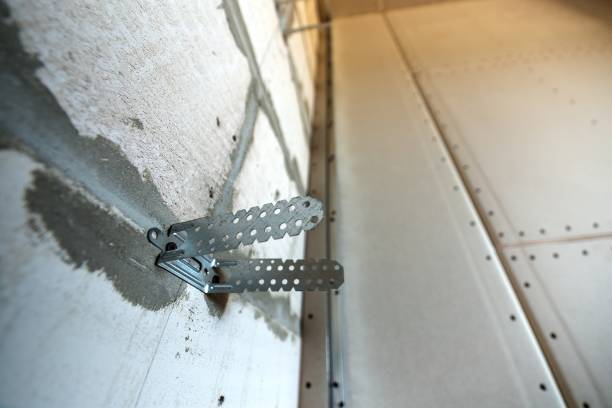 istock Unfinished brick wall in a room under construction prepared for drywall plates frame installation. 1193141665