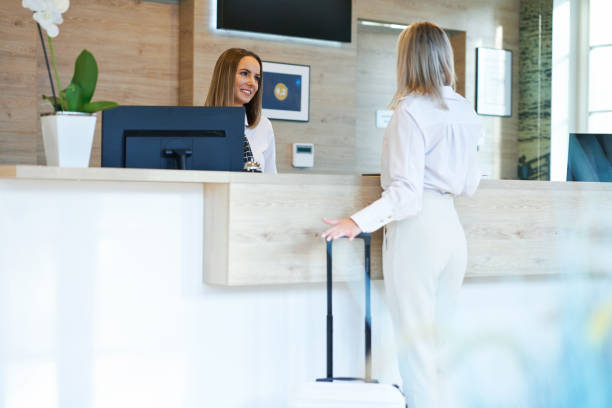 Receptionist and businesswoman at hotel front desk stock photo