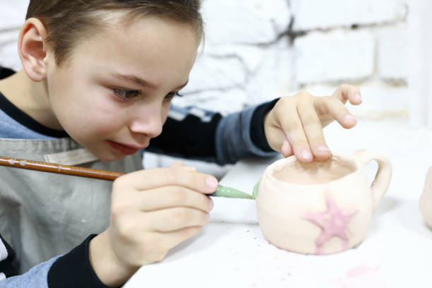 istock Child painting clay mug 1193145016