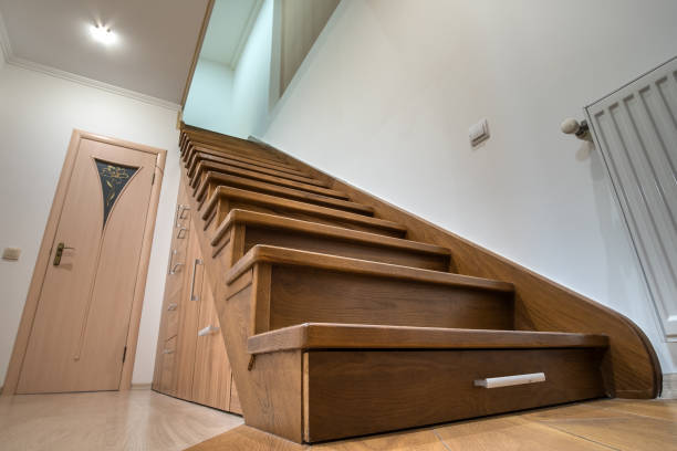 istock Modern architecture interior with luxury hallway with glossy wooden stairs in multi-storey house. Custom built pullout cabinets on glides in slots under stairs. Use of space for storage. 1193145470