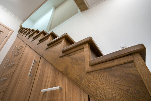 istock Modern architecture interior with luxury hallway with glossy wooden stairs in multi-storey house. Custom built pullout cabinets on glides in slots under stairs. Use of space for storage. 1193145493